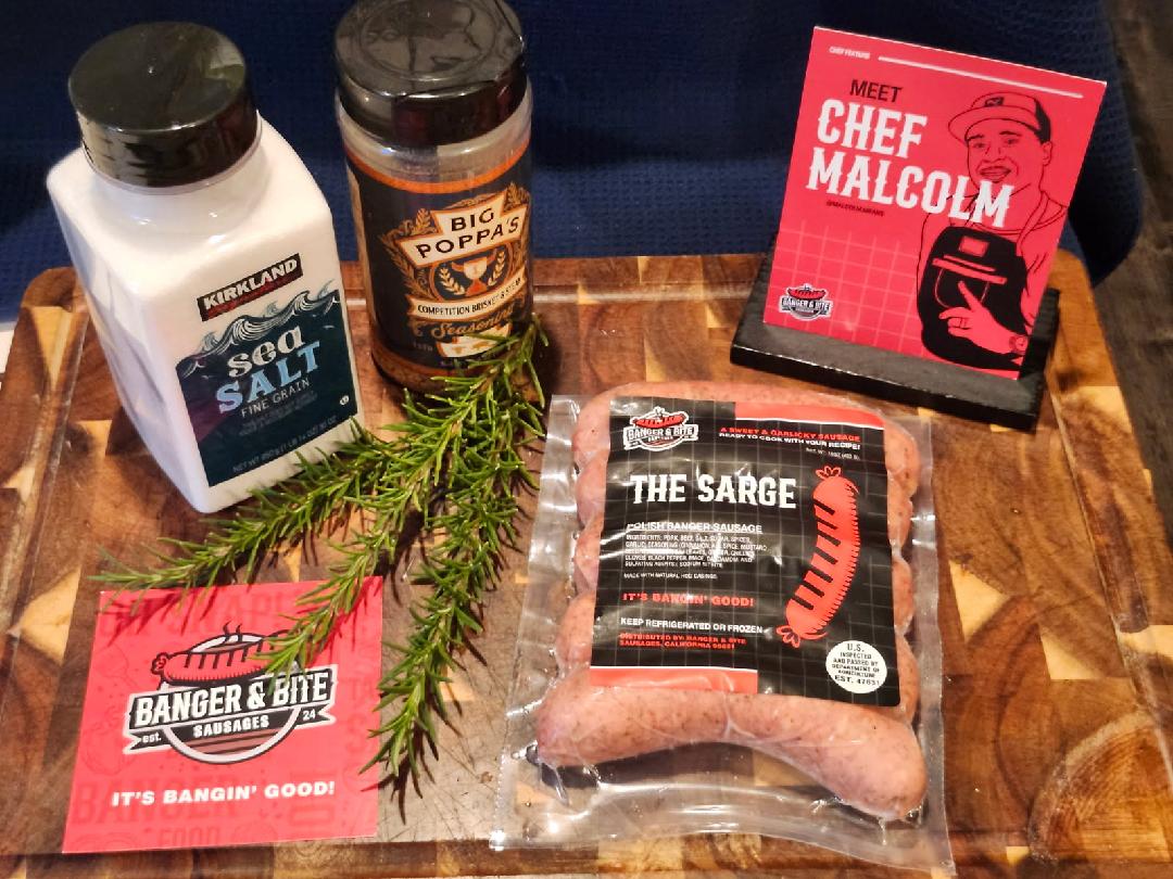 Cutting board display showcasing seasonings, a postcard with an illustrator of the owner, Malcolm, a square thank you card, and "The Sarge" sausage pack