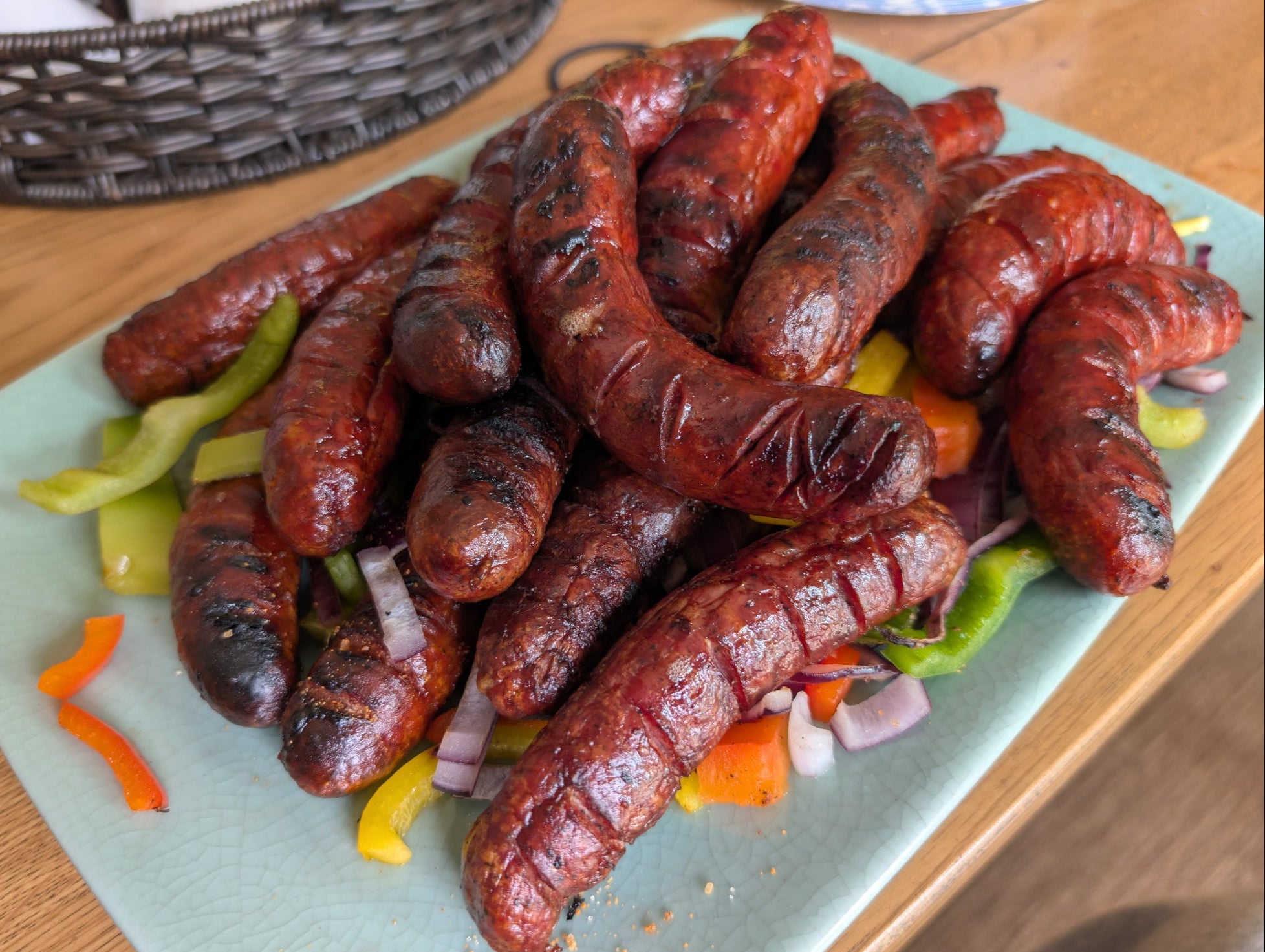 A tray of cooked sausages with grilled peppers and onions ready to eat 