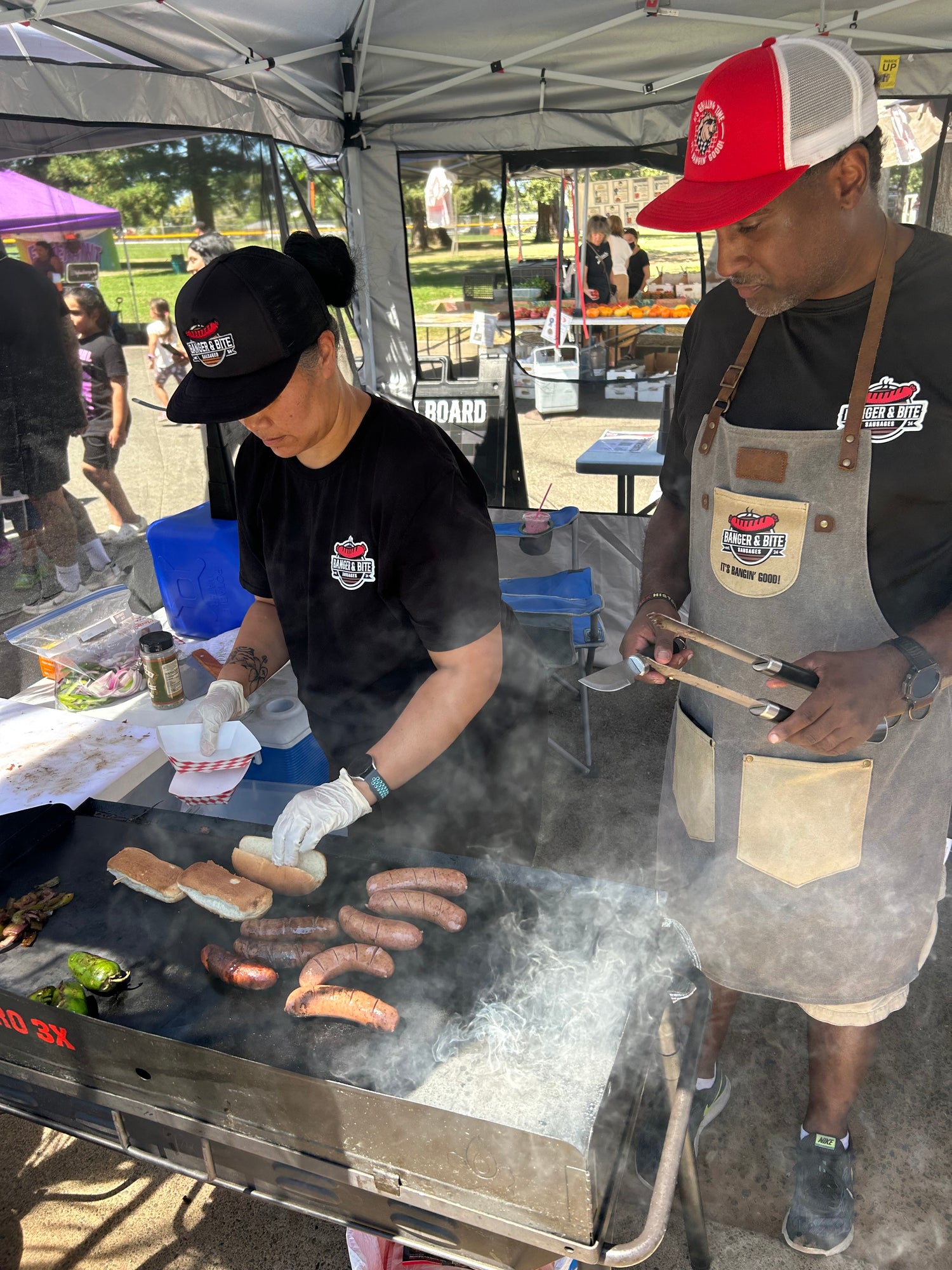 Our founder, Malcolm, standing next to his wife, grilling sausages at a local farmer's market